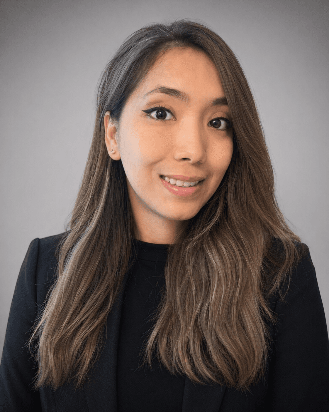 Professional headshot of a smiling woman with long highlighted hair wearing a black blazer.