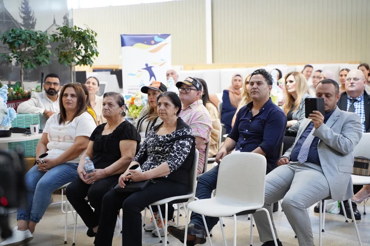 Diverse audience sitting in chairs, attentively watching a presentation at an indoor community event.