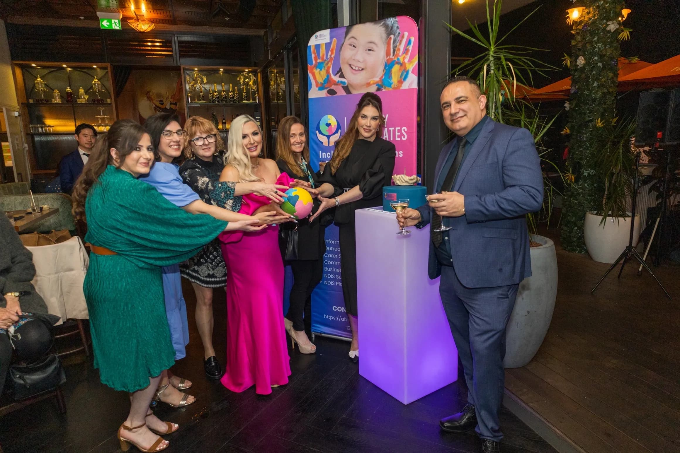 Group of people at an Inclusion Advocates event posing with a colorful heart-shaped object.